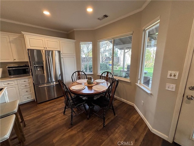 dining room featuring visible vents, ornamental molding, dark wood-style floors, and a healthy amount of sunlight