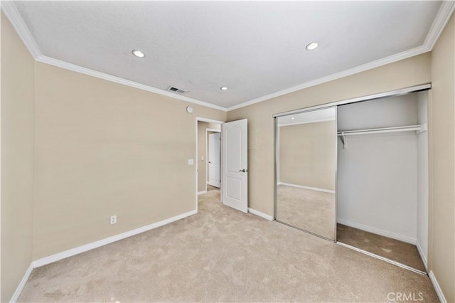 unfurnished bedroom featuring crown molding, light carpet, and a closet