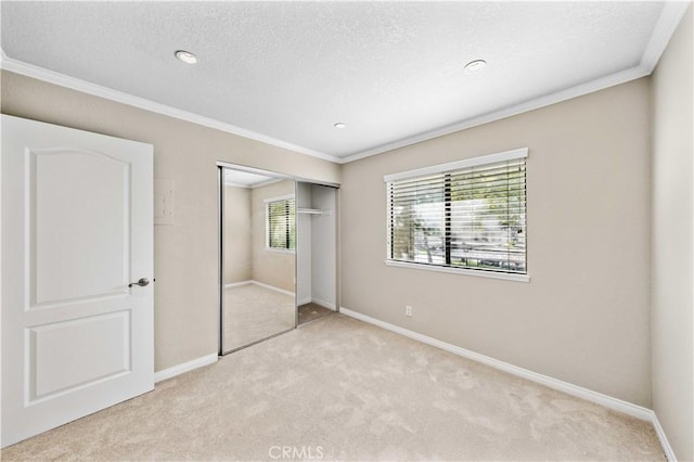 unfurnished bedroom with crown molding, light colored carpet, a closet, and a textured ceiling