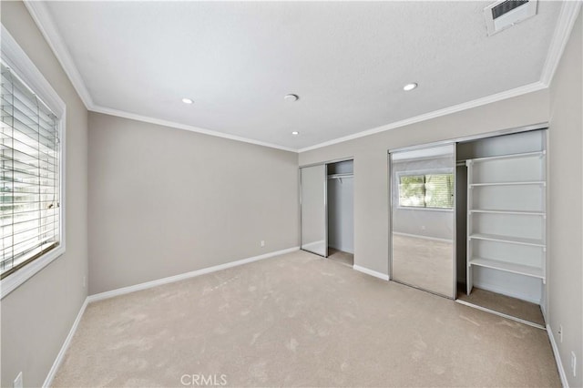 unfurnished bedroom featuring light carpet, crown molding, and multiple closets