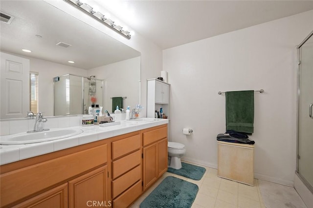 bathroom with a shower with door, vanity, tile patterned floors, and toilet