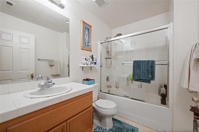 full bathroom with tile patterned flooring, bath / shower combo with glass door, vanity, and toilet