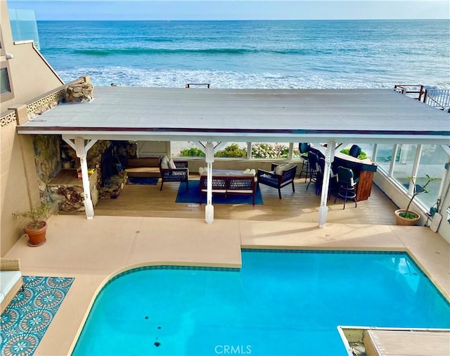 view of pool with a water view, an outdoor hangout area, and a view of the beach