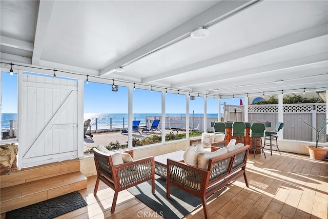 sunroom / solarium featuring beam ceiling and a water view