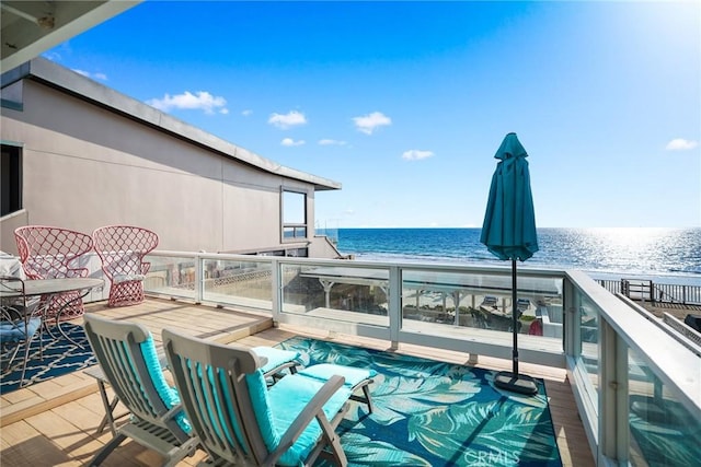 balcony with a water view and a view of the beach