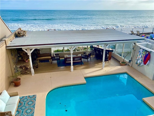 view of swimming pool with a water view, an outdoor hangout area, and a view of the beach