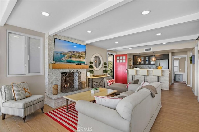 living room with a fireplace, beam ceiling, and light hardwood / wood-style floors