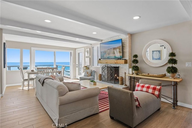 living room with a fireplace, light hardwood / wood-style flooring, and beamed ceiling