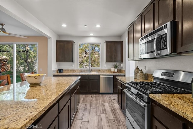 kitchen with stainless steel appliances, light stone countertops, light hardwood / wood-style floors, and plenty of natural light