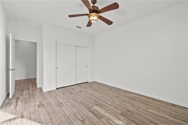 unfurnished bedroom featuring light hardwood / wood-style flooring, a closet, and ceiling fan