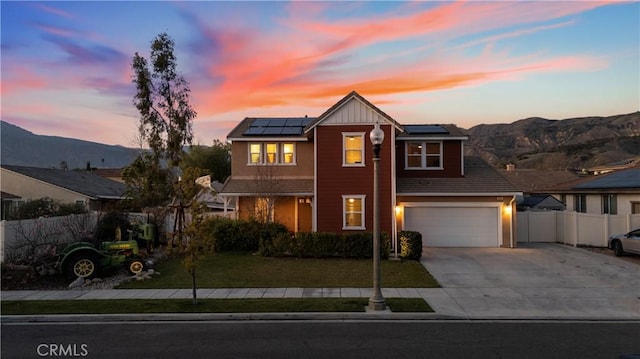 view of front of property with driveway, solar panels, fence, a mountain view, and board and batten siding