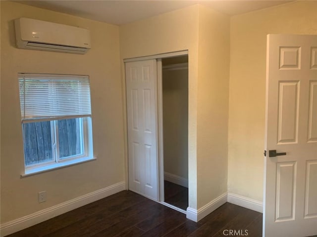 unfurnished bedroom with dark hardwood / wood-style floors, a wall mounted AC, and a closet