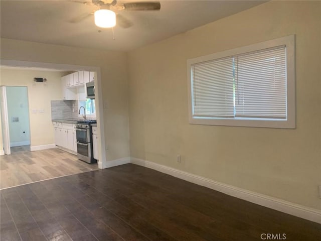 unfurnished living room featuring sink, dark hardwood / wood-style floors, and ceiling fan