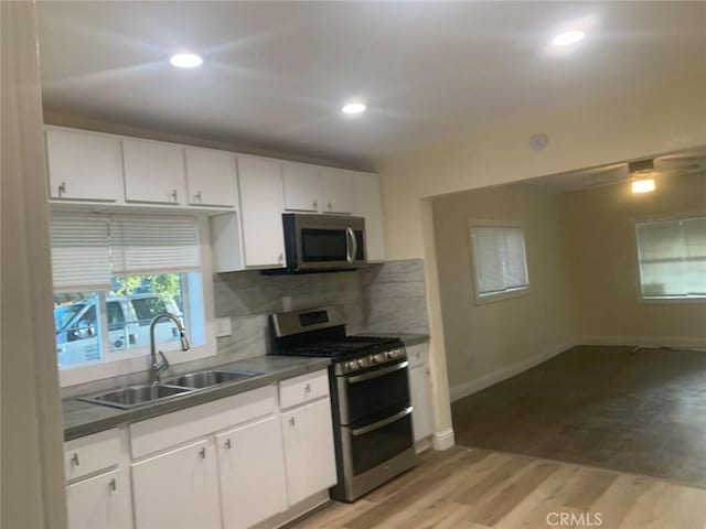 kitchen with white cabinetry, sink, stainless steel appliances, and light wood-type flooring