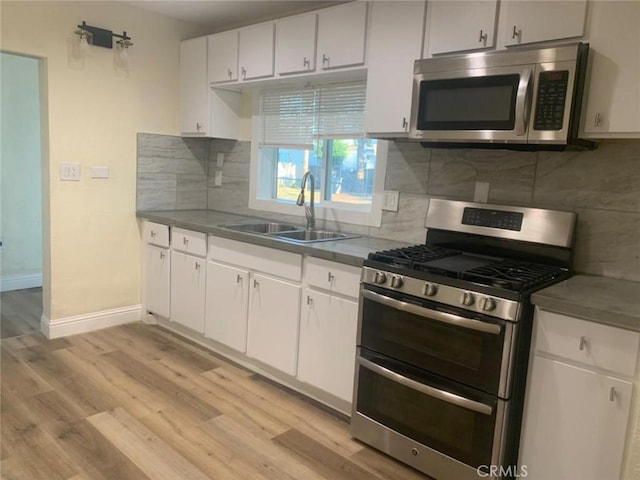 kitchen with sink, white cabinets, decorative backsplash, stainless steel appliances, and light wood-type flooring