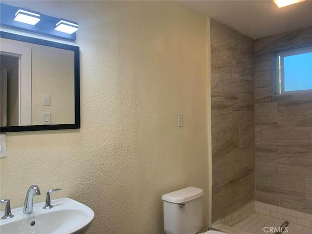 bathroom with sink, toilet, and tiled shower