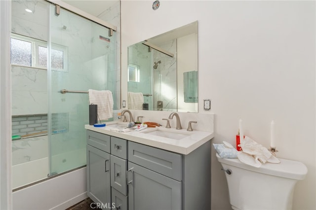 full bathroom featuring vanity, combined bath / shower with glass door, and toilet