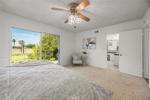 carpeted bedroom featuring a ceiling fan, visible vents, a textured ceiling, and ensuite bathroom