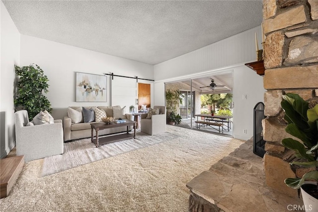 living area featuring a barn door, a fireplace, and a textured ceiling