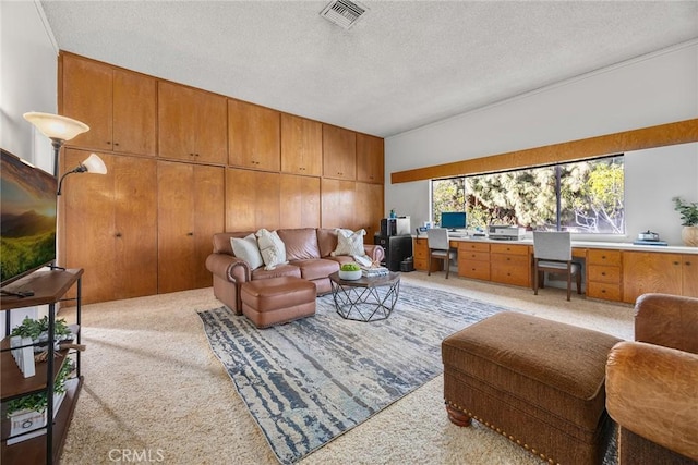 carpeted living area featuring built in desk, visible vents, and a textured ceiling