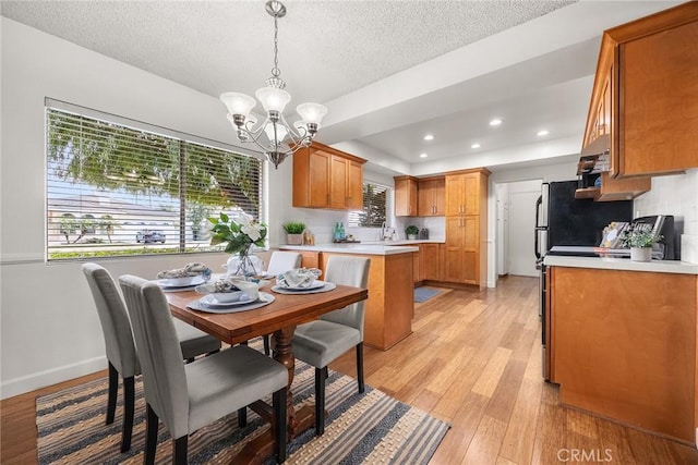 dining space featuring a notable chandelier, light hardwood / wood-style floors, and a textured ceiling