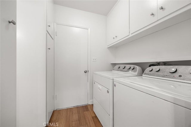 laundry area featuring light wood-style floors, cabinet space, and washer and dryer