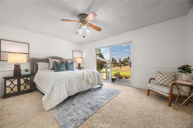 carpeted bedroom featuring access to outside, ceiling fan, and a textured ceiling