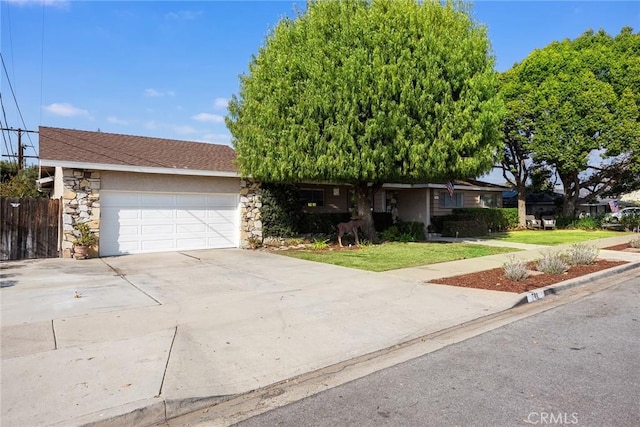 single story home featuring a garage, stone siding, a front yard, and driveway