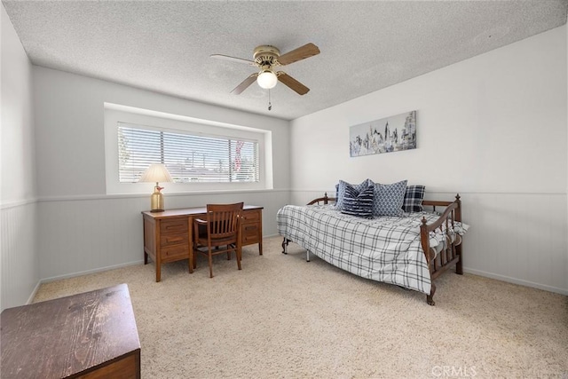 bedroom with ceiling fan, light colored carpet, and a textured ceiling