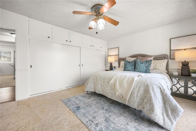 bedroom featuring ceiling fan, a closet, a textured ceiling, and carpet