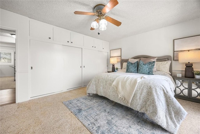 carpeted bedroom with ceiling fan, a closet, and a textured ceiling