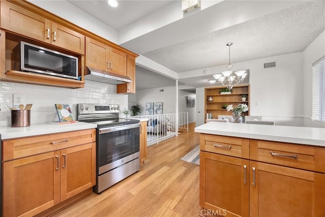 kitchen with under cabinet range hood, stainless steel appliances, visible vents, light countertops, and light wood-type flooring