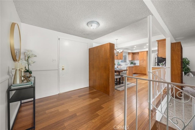 entryway featuring wood-type flooring, an inviting chandelier, and a textured ceiling