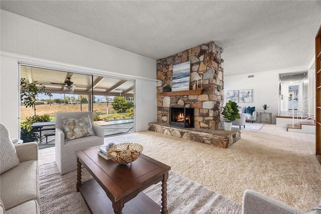 carpeted living area featuring a textured ceiling, ceiling fan, a fireplace, and visible vents