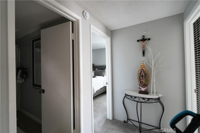 hallway with carpet and a textured ceiling