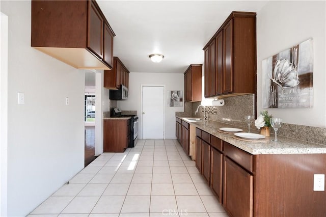 kitchen featuring sink, light tile patterned floors, appliances with stainless steel finishes, light stone countertops, and decorative backsplash