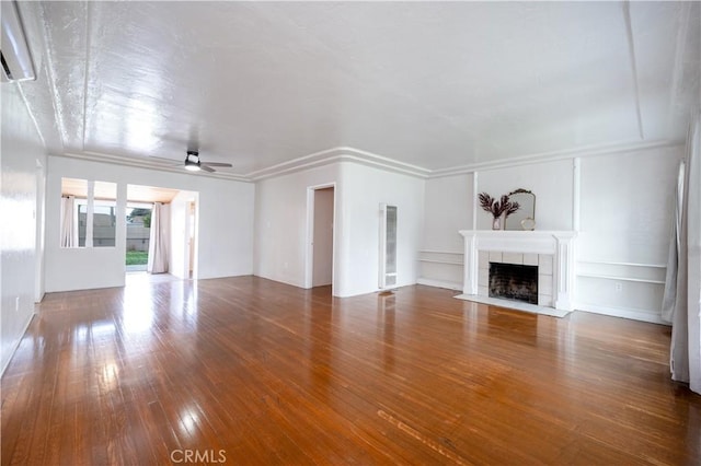 unfurnished living room featuring a tiled fireplace, wood-type flooring, and ceiling fan