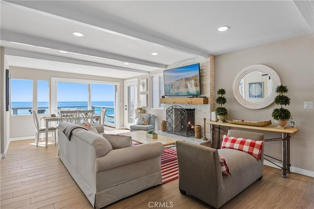 living room featuring beam ceiling, a fireplace, and light hardwood / wood-style floors