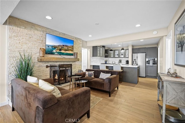 living room featuring a stone fireplace and light hardwood / wood-style floors