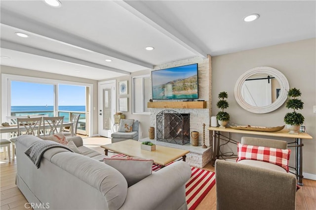 living room with a fireplace, beamed ceiling, and light wood-type flooring