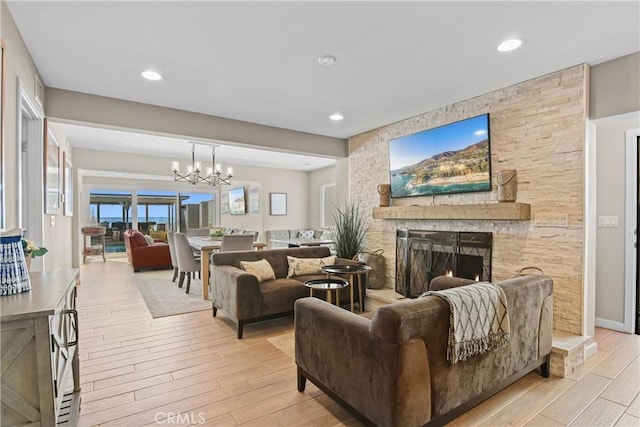 living room with a fireplace, a chandelier, and light wood-type flooring