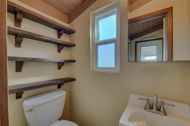 bathroom with lofted ceiling with beams, toilet, sink, and wooden ceiling