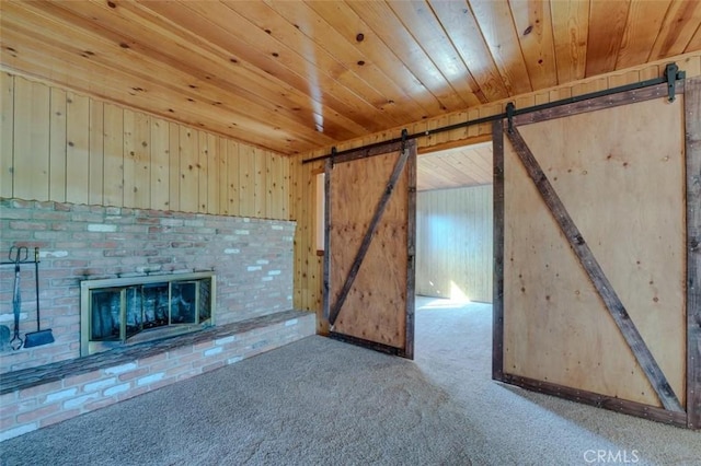 unfurnished living room with wood walls, a barn door, carpet floors, and wooden ceiling