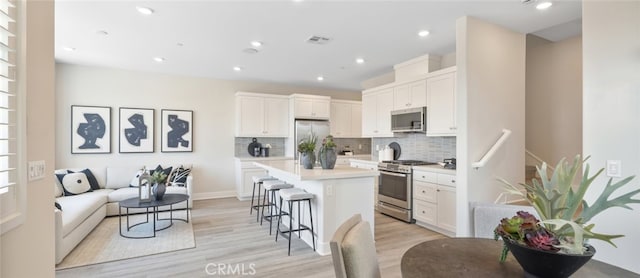 kitchen with appliances with stainless steel finishes, a breakfast bar area, a kitchen island, and white cabinets