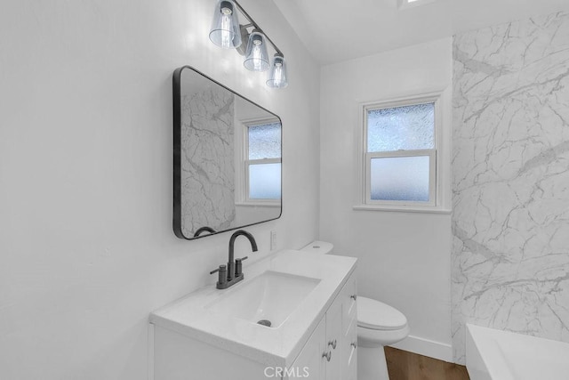 bathroom with vanity, a tub, hardwood / wood-style floors, and toilet