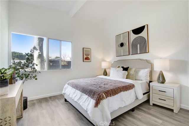 bedroom with beamed ceiling and light wood-type flooring