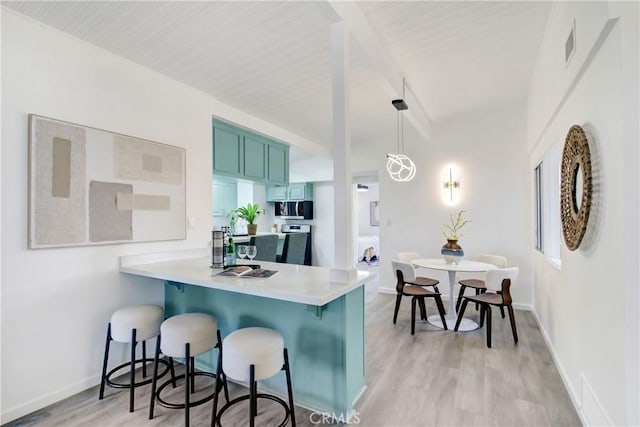 kitchen featuring stove, decorative light fixtures, kitchen peninsula, and light wood-type flooring