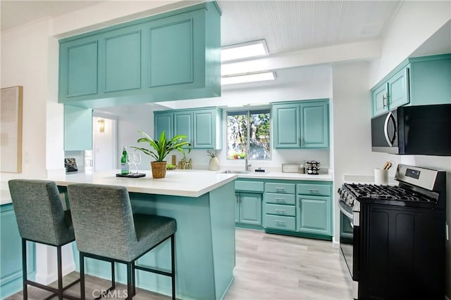 kitchen featuring sink, a breakfast bar, kitchen peninsula, and appliances with stainless steel finishes