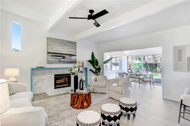 living room with a brick fireplace, beam ceiling, light hardwood / wood-style flooring, and ceiling fan