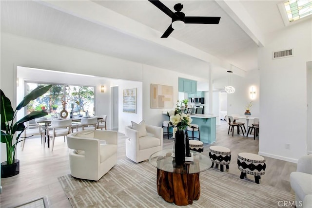 living room featuring ceiling fan, beam ceiling, a skylight, and light hardwood / wood-style floors